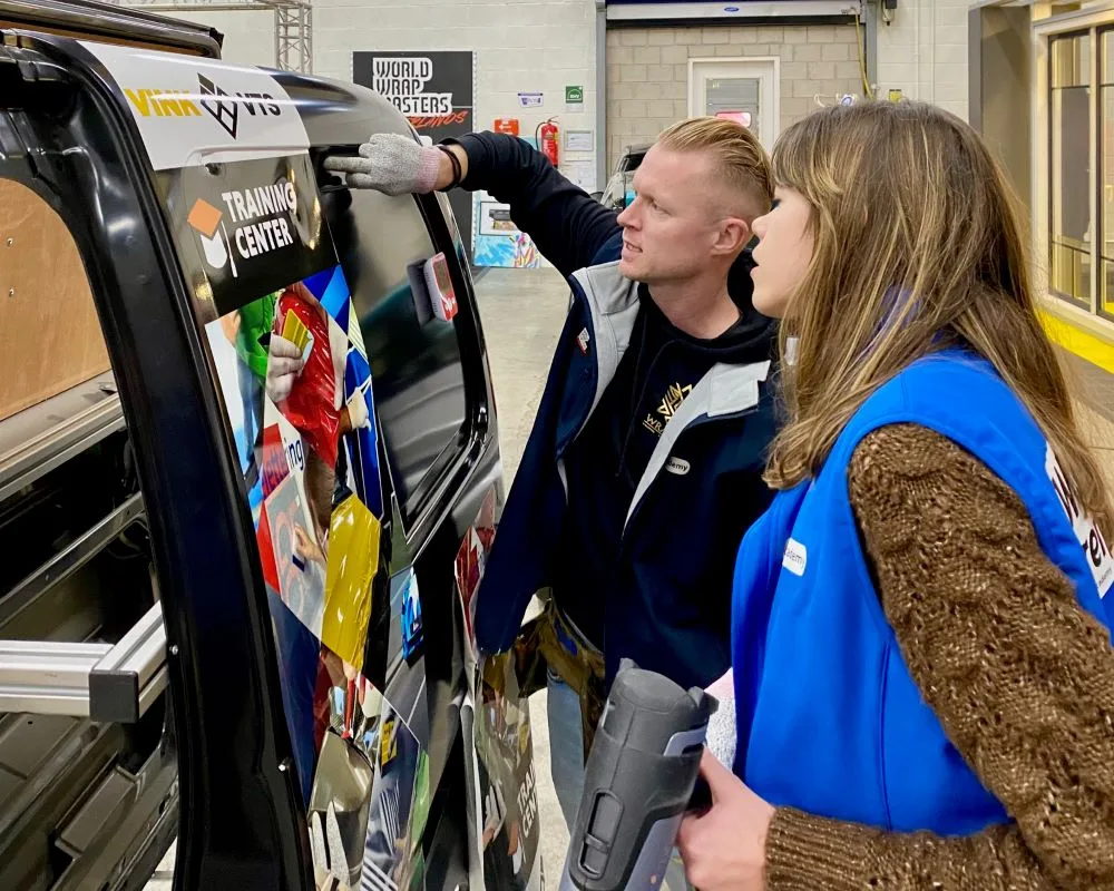 Trainer demonstreert aan cursist hoe je printfolie op de juiste manier inwerkt in een profiel van een bestelbus tijdens de Appcademy signmaker advanced opleiding en training