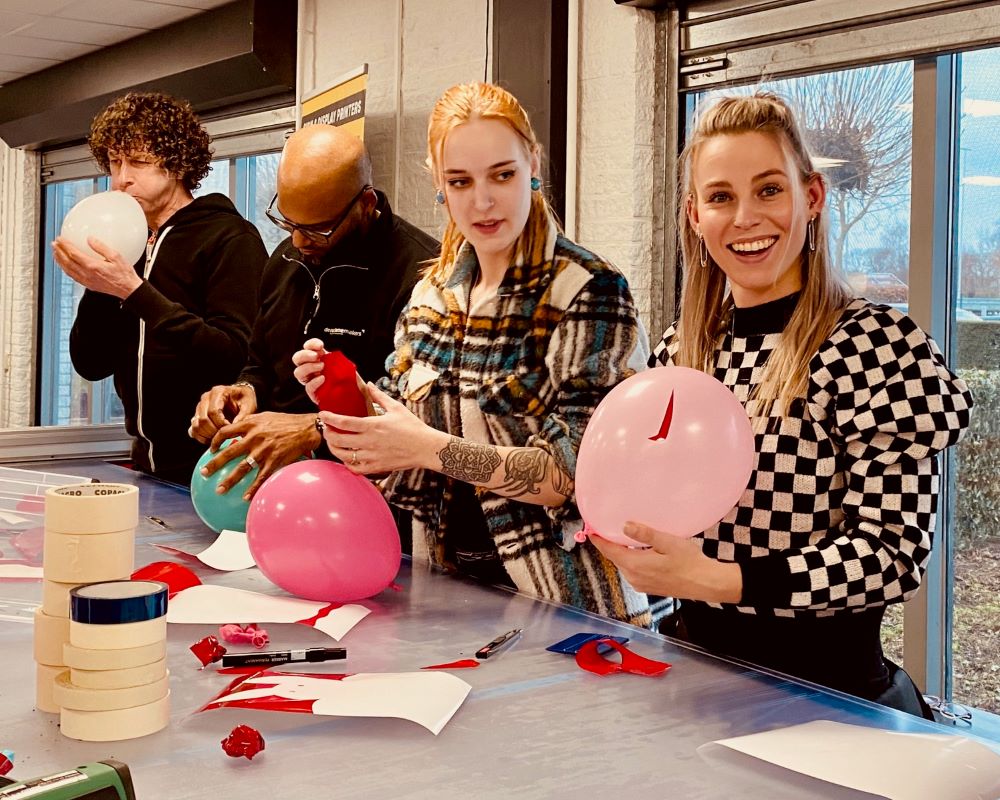 Cursisten verbeteren hun skills door snijfolies af te snijden op ballonnen tijdens de Appcademy opleiding signmaker training