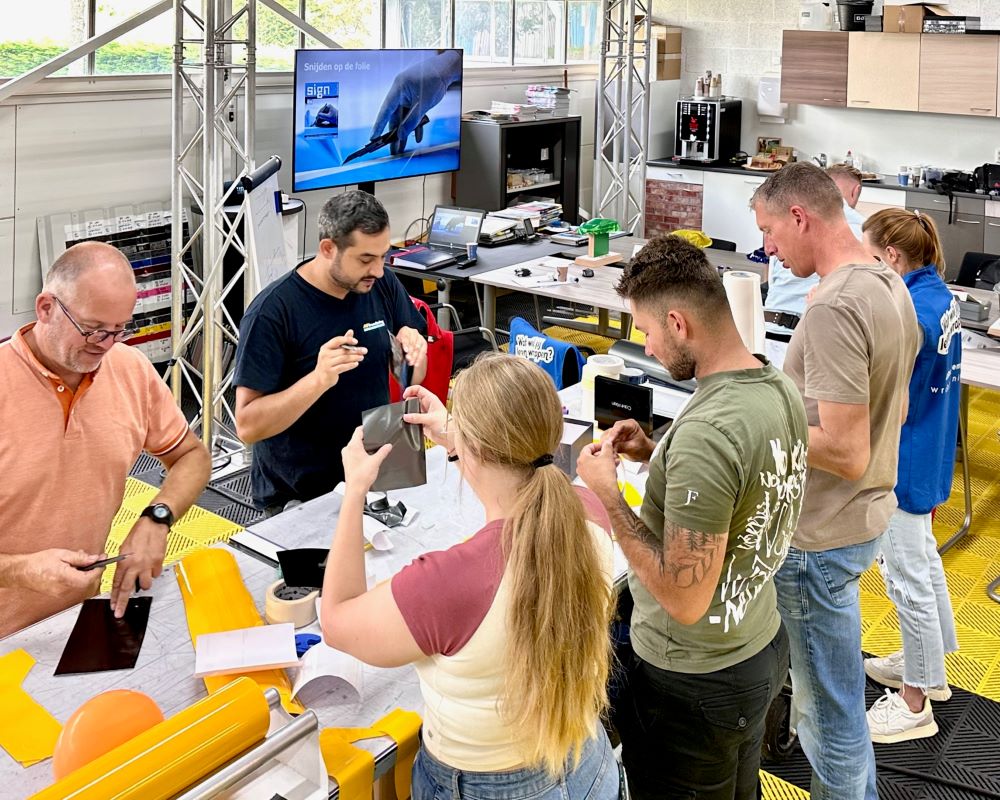 Cursisten verbeteren hun vaardigheden door snijfolies af te snijden op ballonnen tijdens de Appcademy signmaker training en cursus