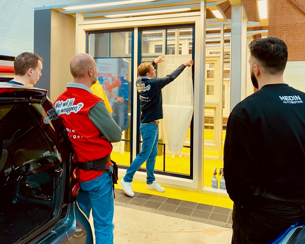 Trainer demonstreert het nat plakken van folies op ramen tijdens de Appcademy signmaker workshop