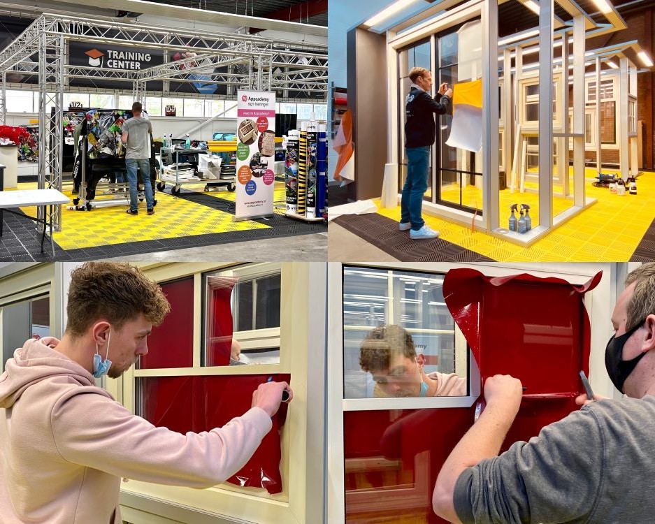 Trainer en cursisten plakken zelfklevende folie op ruiten als praktijk oefening tijdens de Appcademy signmaker opleiding cursus