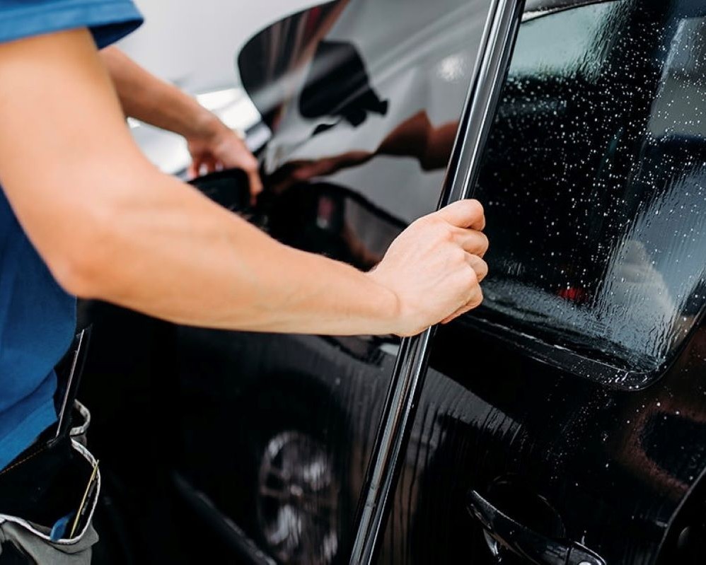 Foto van het uitmeten van raamfolie bij een zijruit tijdens Appcademy Automotive Windowfilm training