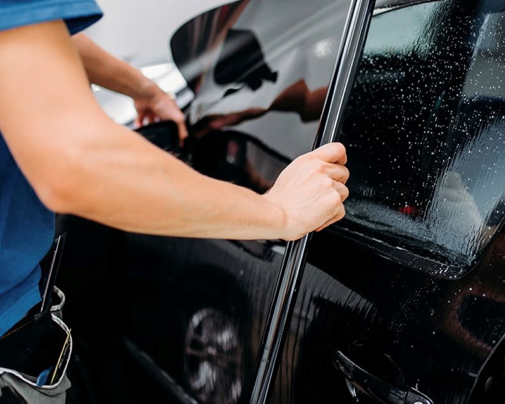 Foto van het uitmeten van raamfolie bij een zijruit tijdens Appcademy Automotive Windowfilm training