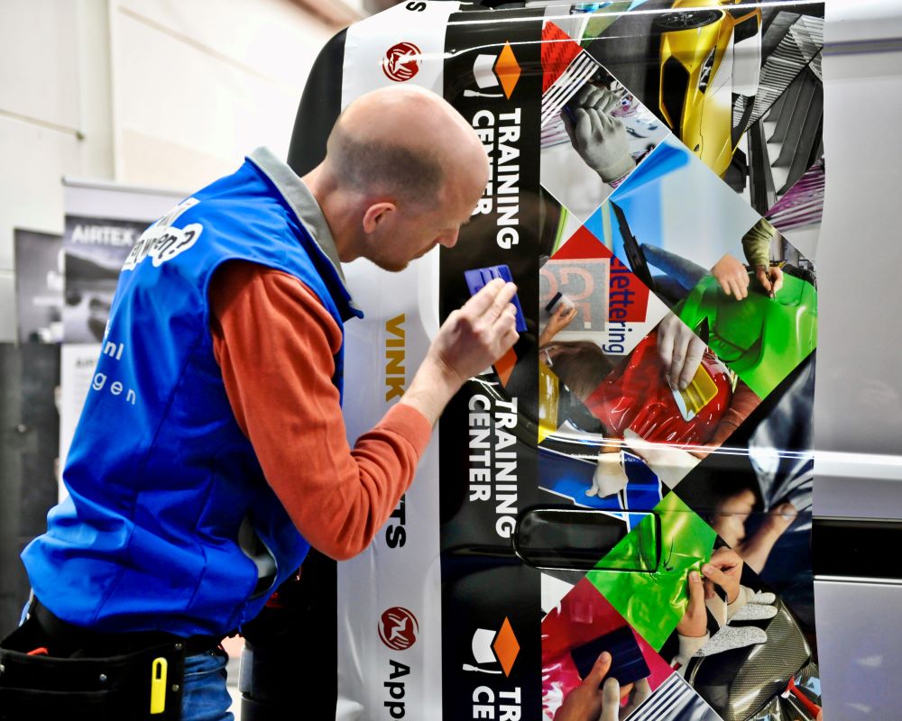 Cursist wrapt printfolie in een diep profiel als praktijkoefening tijdens de Appcademy signmaker advanced training