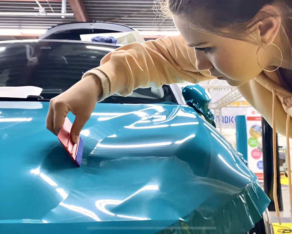 Cursist oefent wrap van achterklep auto tijdens carwrap cursus Appcademy