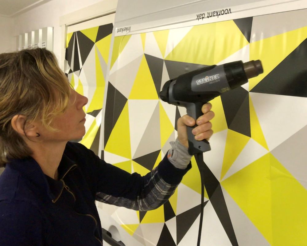 Cursist föhnt en verwarmt printfolie in een profiel als praktijkoefening tijdens de Appcademy signmaker advanced training