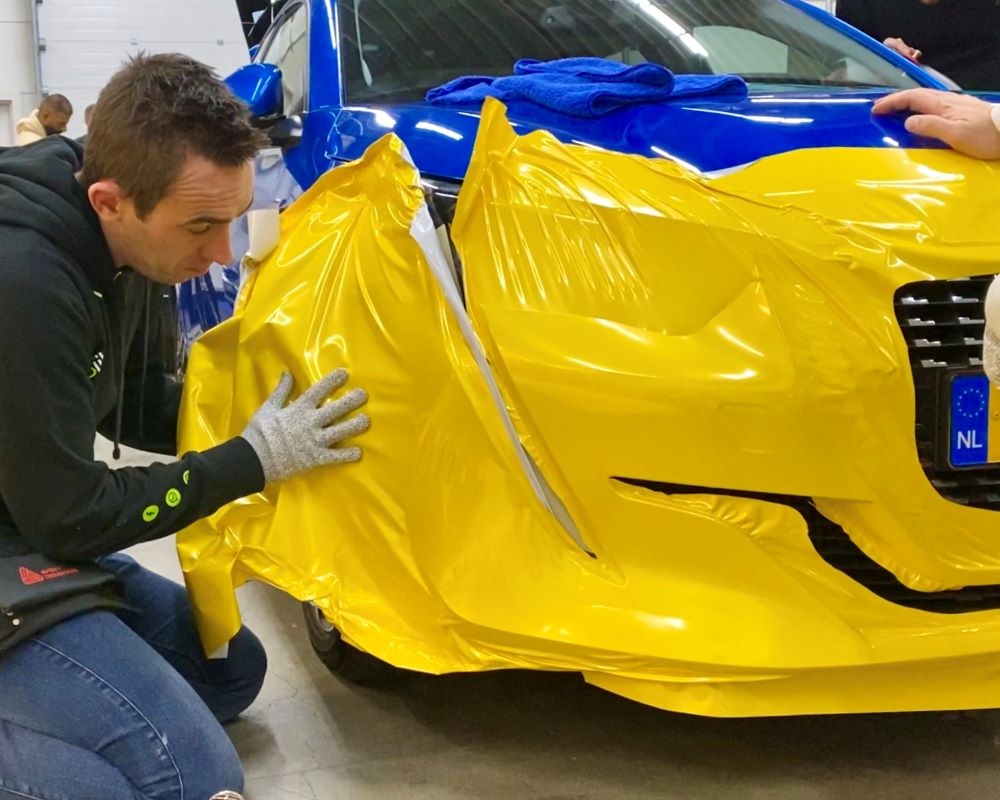 Cursist doet praktijkoefening wrappen van een moeilijke bumper tijdens Appcademy Carwrap Masterclass cursus