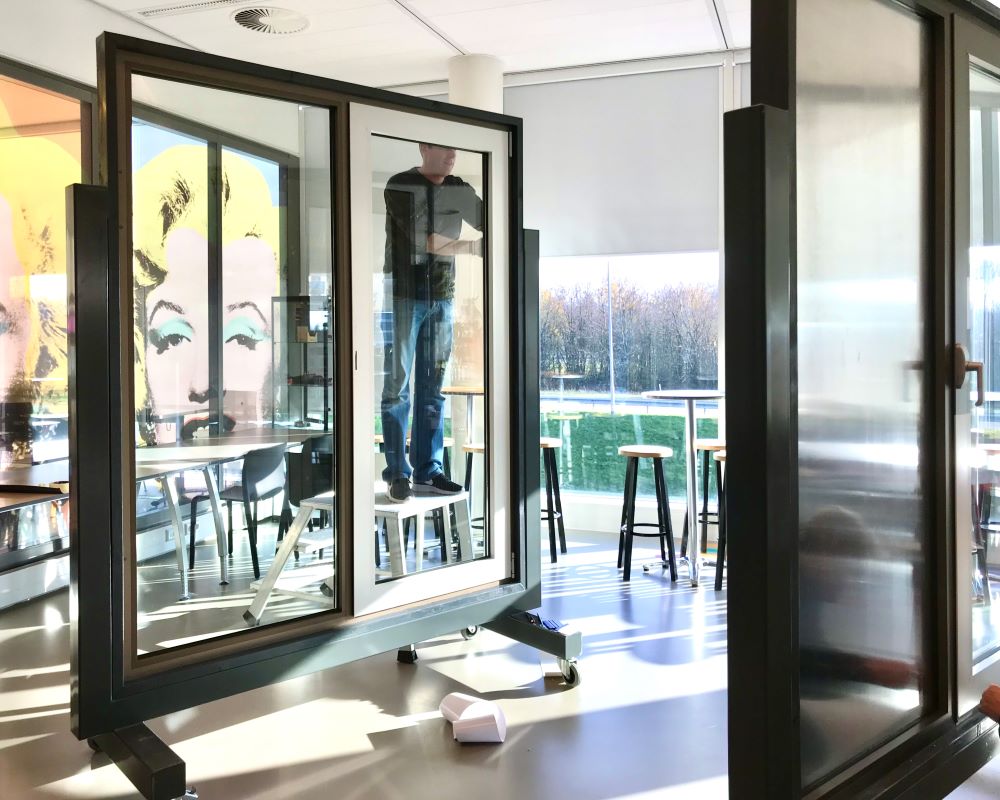 Cursist staat op trap terwijl hij Facadefilm kozijnfolie plakt op aluminium kozijn tijdens “Schilderen met folie” Facadefilm cursus