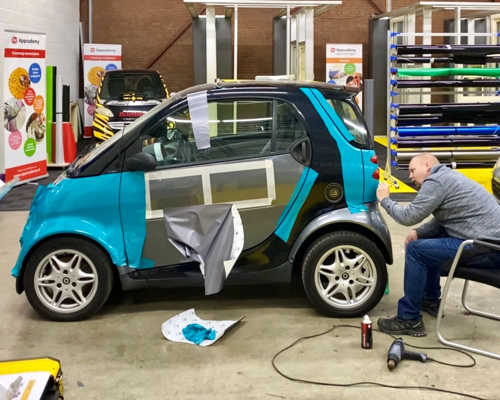 Cursist doet praktijkoefening carwrapfolie afwerken tijdens Appcademy workshop