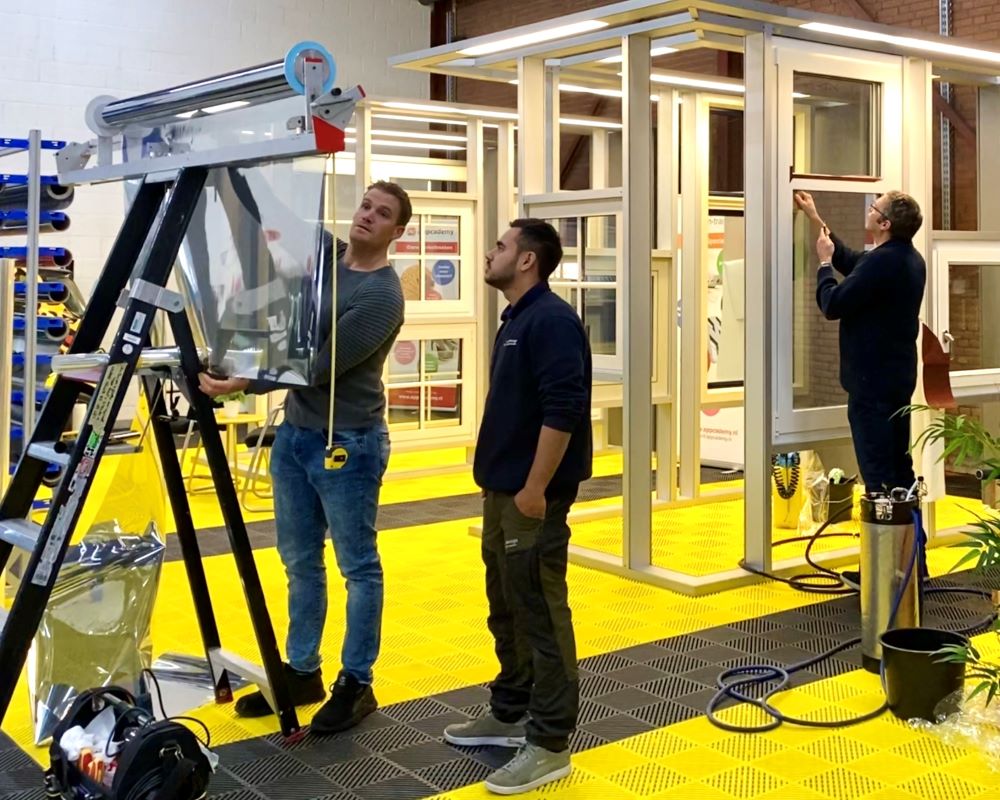 Cursisten snijden raamfolie op maat met folie dispencer bij Appcademy Architectural Windowfilm opleiding