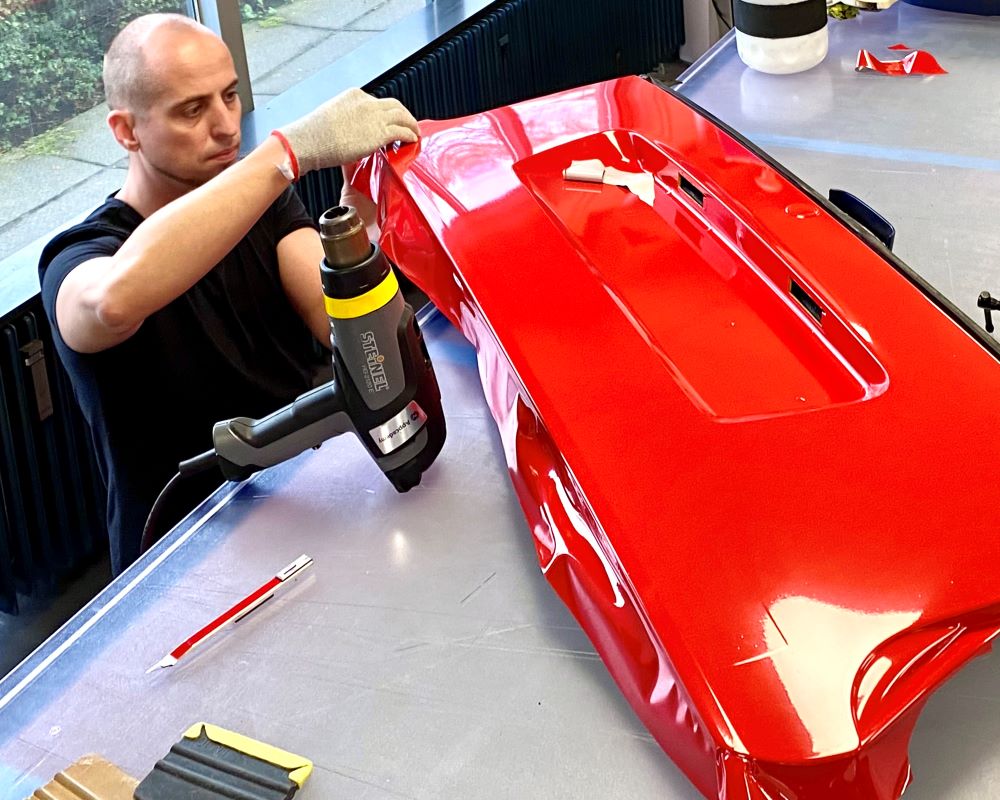 Cursist doet praktijkoefeningwrappen achterklep tijdens carwrap training opleiding Appcademy