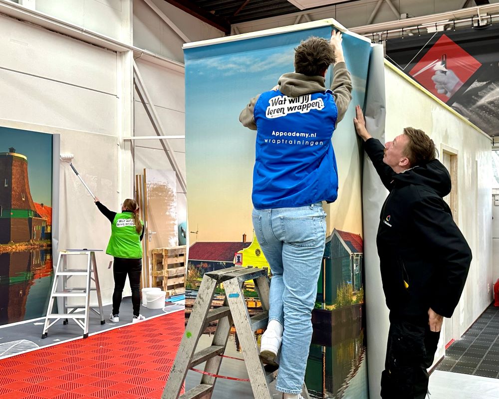 Cursisten plakken naadloos fotobehang om de hoek van een wand tijdens Appcademy Naadloos fotobehang cursus