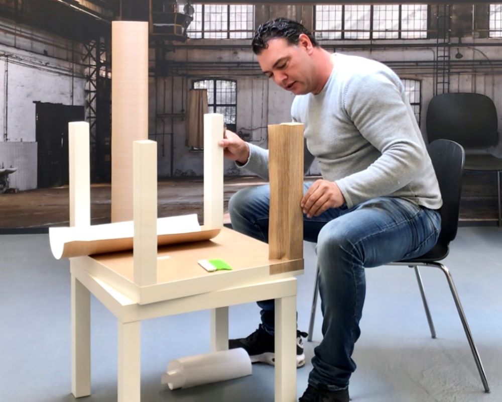 Cursist wrapt een tafel met tafelpoten als praktijkoefening tijdens de Appcademy training en opleiding interieurfolie plakken en keukens wrappen