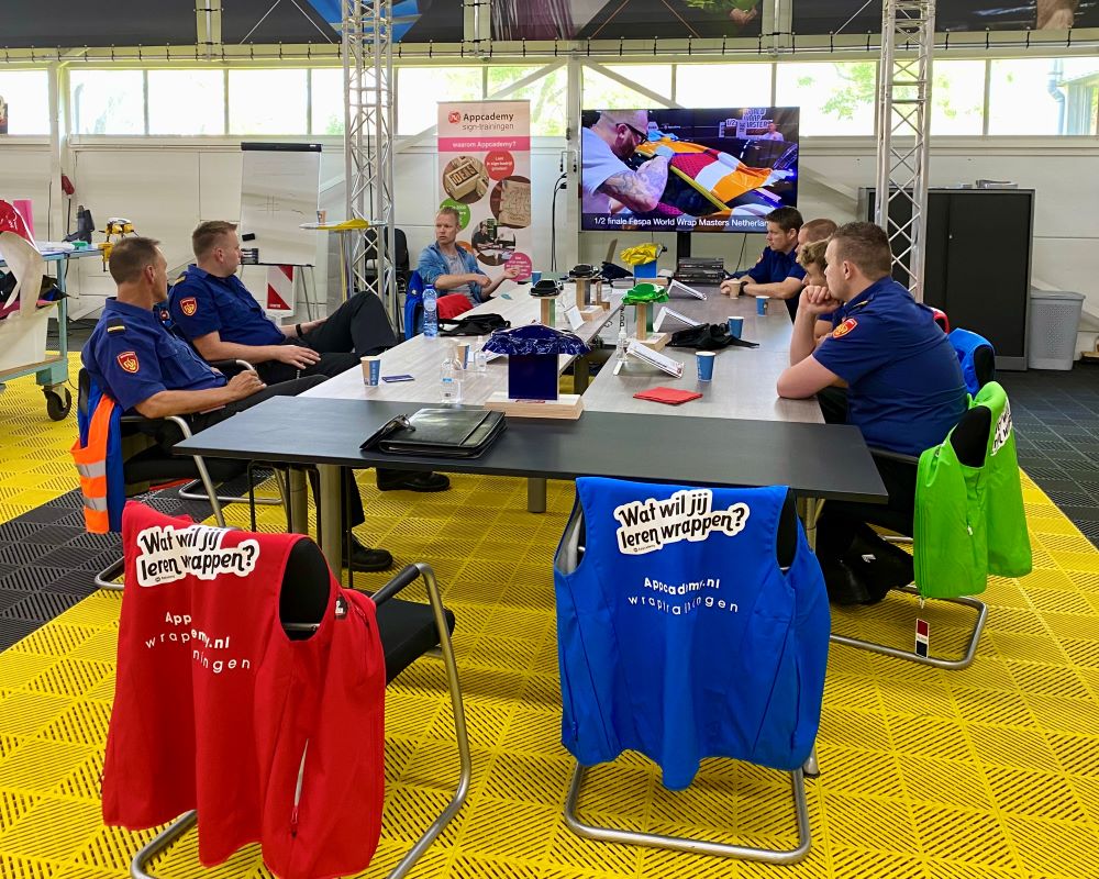 Trainer zit aan tafel met cursisten brandweer en deelt informatie over carwrapping tijdens Appcademy carwrap cursus