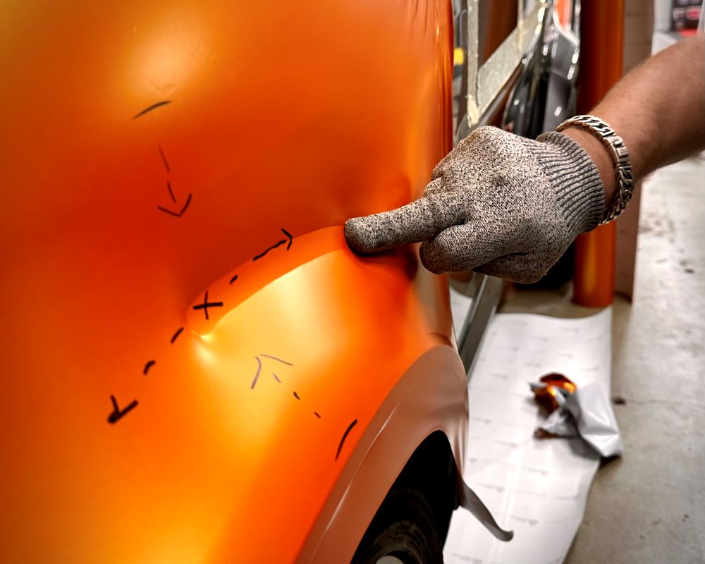 Trainer demonstreert carwrap techniek bij wrappen van auto tijdens Appcademy carwrap cursus