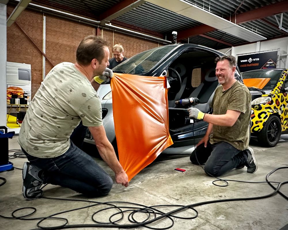 Cursisten wrappen voorscherm spatbord auto als praktijkoefening tijdens Appcademy carwrap cursus