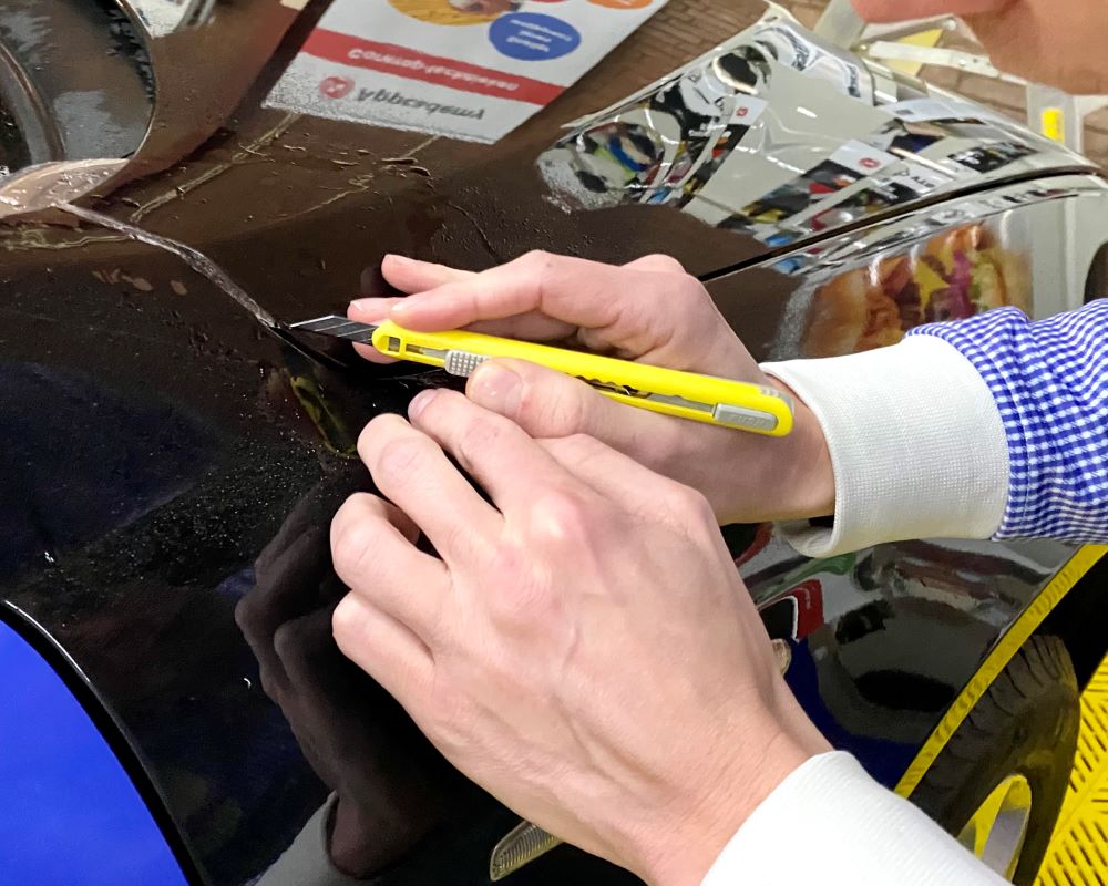 Cursist werkt als praktijkoefening PPF folie af bij carosserie rand tijdens Appcademy Paint Protection Film cursus