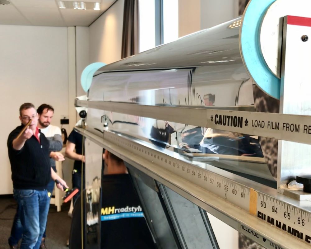 Trainer geeft aanwijzingen i.v.m. afsnijden van raamfolie met folie dispencer tijdens Appcademy Architectural Windowfilm training