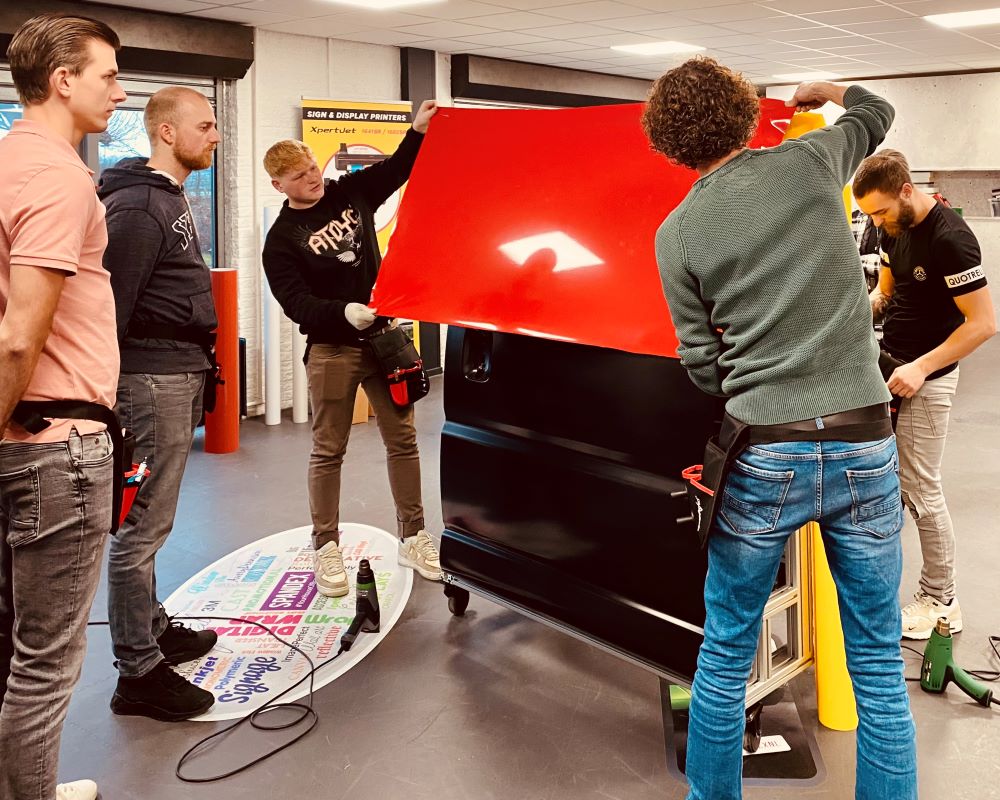 Cursisten leggen zelfklevende folies op een oefenpaneel tijdens de Appcademy signmaker advanced training