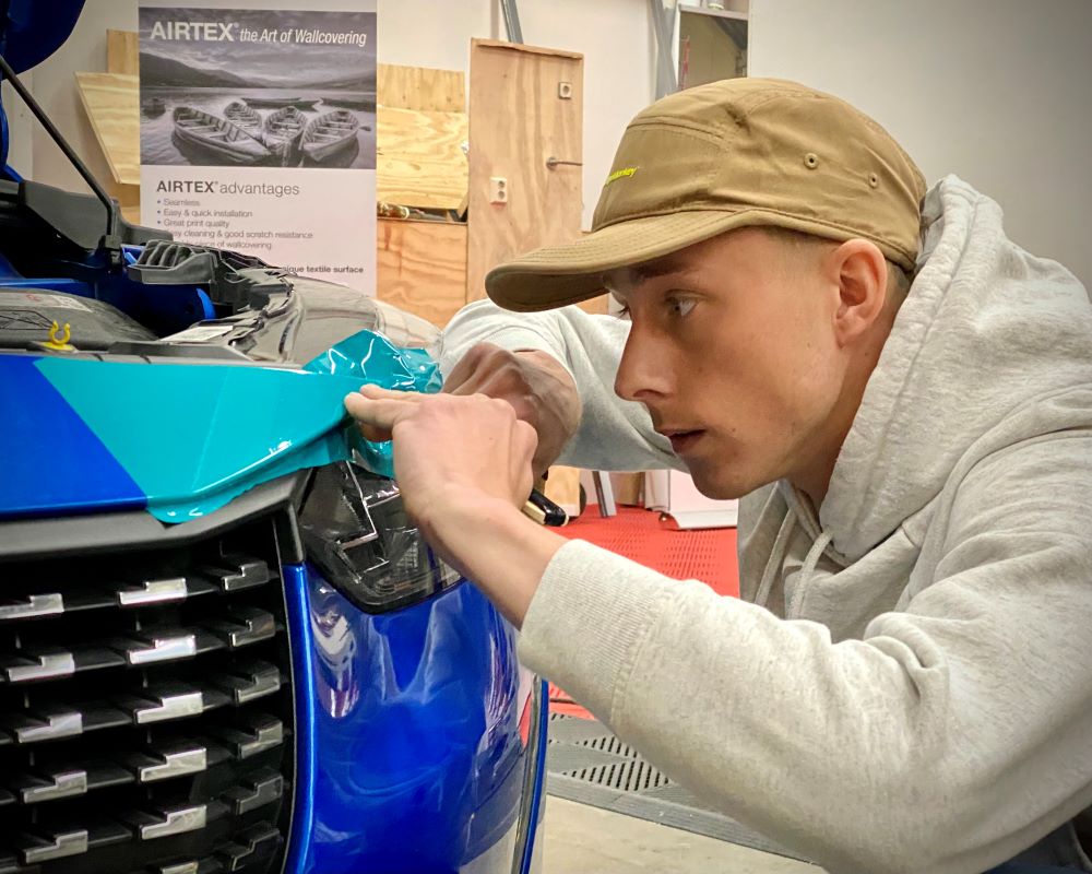 Cursist oefent afwerking carwrapfolie tijdens Appcademy cursus