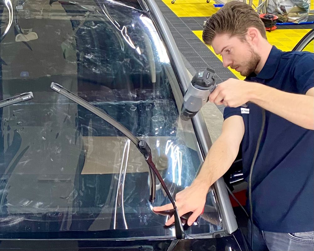 Trainer demonstreert op maat krimpen van raamfolie bij te plakken voorruit tijdens Appcademy Automotive Windowfilm cursus