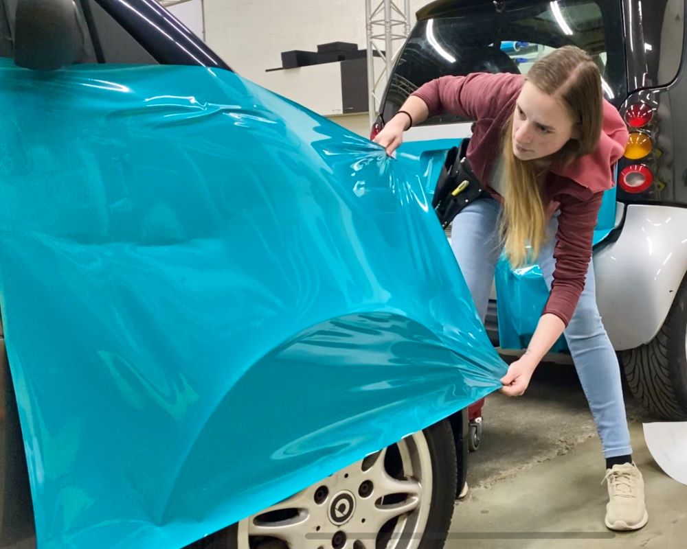 Cursist carwrapt zijkant auto als praktijkoefening tijdens Appcademy carwrap cursus