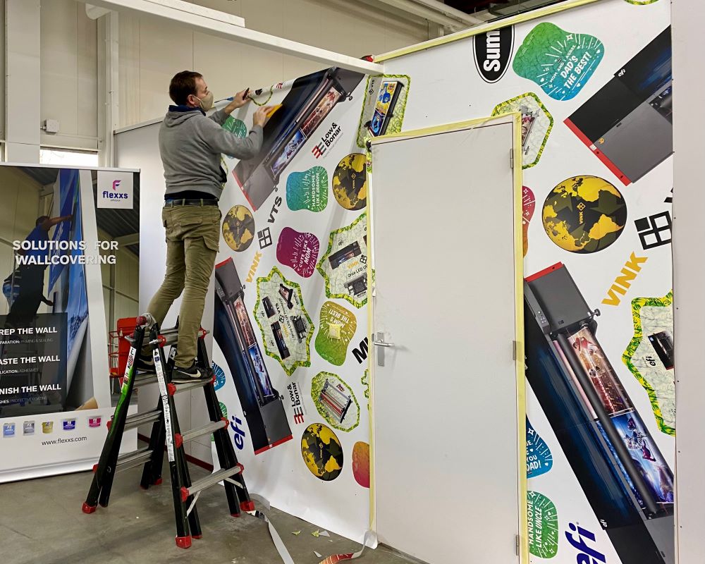 Cursist plakt naadloos fotobehang Airtex als praktijkoefening tijdens deelname Appcademy Naadloos fotobehang cursus